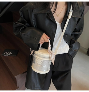 Détail du sac seau blanc cylindrique avec poignée en soie et bande argentée texturée