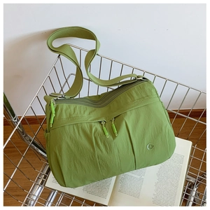 Detail of lime green nylon crossbody bag with multiple zippers inside a metal shopping cart