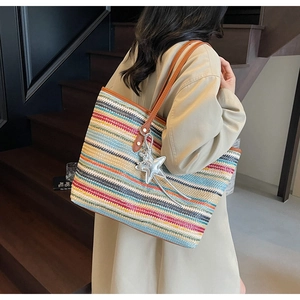 Detail der bunt gestreiften Strohtasche mit braunen Ledergriffen und Sternanhänger