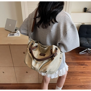 Detail of large beige hobo tote with brown leather straps and silver eyelet accents