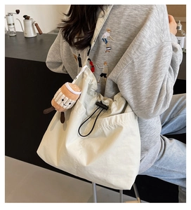 Détail du sac fourre-tout crème avec cordon de serrage et pendentif tasse à café peluche