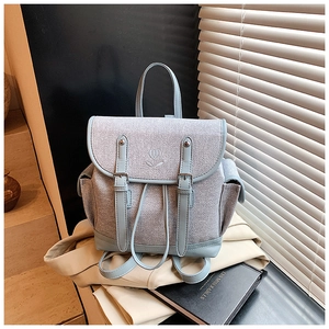 Detail of light blue backpack featuring floral embroidery and silver metal buckles