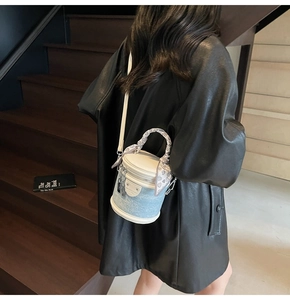 Vue détaillée d'un sac cylindrique bleu pailleté avec poignée en foulard sur escalier