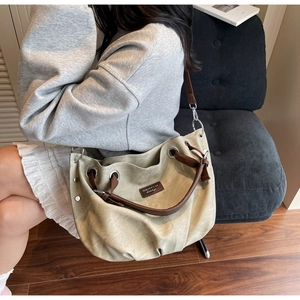 Detail of a khaki large-capacity tote bag with brown leather straps and metal rivets