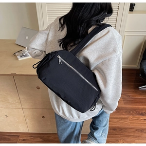 Close-up of black nylon shoulder bag with silver zipper and side drawstring detail