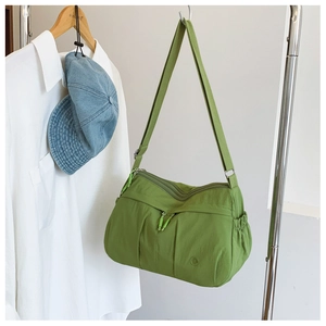 Detailed view of green nylon crossbody bag with multiple zip pockets and wide strap