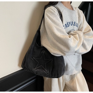 Detail of black denim hobo bag featuring a 3D star embossed design and shoulder strap