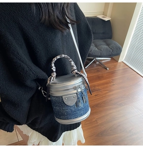 Détail d'un mini sac seau en denim avec perles et poignée enveloppée d'un foulard en soie