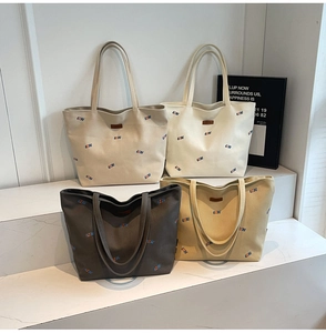 Detail of four canvas tote bags with QZBG embroidery in beige, white, grey, and brown