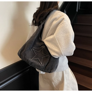 Detail view of washed black denim tote bag with 3D star pattern on a model