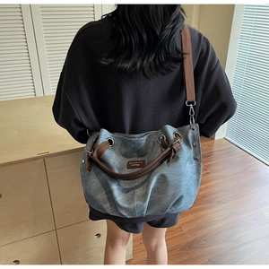 Detail view of light blue vintage large tote bag with brown straps worn by a model
