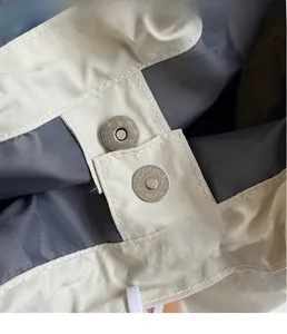 Gros plan du fermoir magnétique et de la texture du tissu sur le cabas beige