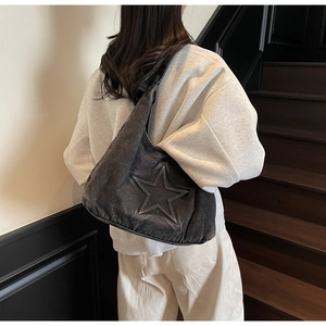 Detailed view of grey denim tote bag with 3D embossed star worn by model on shoulder