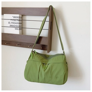 Detail of lime green nylon crossbody bag with functional zip pockets on wooden hanger