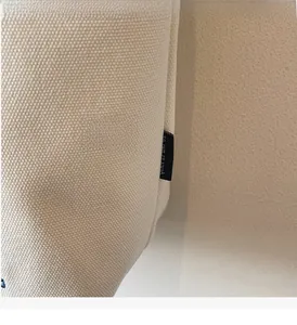 Close-up of durable canvas tote bag side seam with decorative black textile label