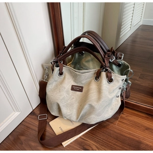Close-up of canvas tote bag with brown leather trim and metal ring hardware detail