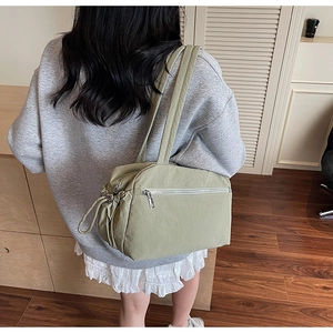 Detail view of light green canvas tote bag with side drawstring shown on a model