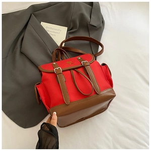 Detail of red canvas and brown leather vintage backpack with dual buckles and side pocket