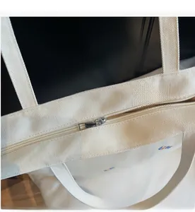 Detail view of the high-quality silver metal zipper and white canvas handle on tote bag