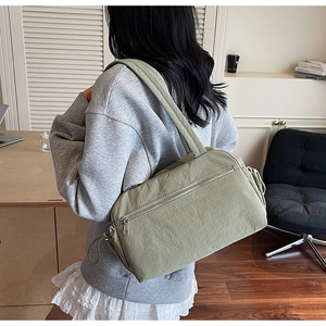 Rear view of a minimalist light green nylon tote bag worn on a shoulder for daily commute