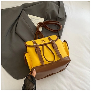 Detail of yellow canvas backpack with brown leather trim and heart embroidery detail