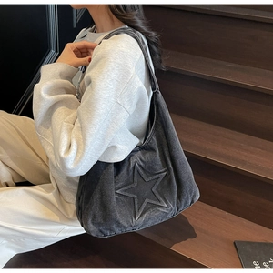 Detail of grey denim tote bag with embossed star pattern on a wooden background