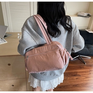 Close-up of pink nylon tote bag showing water-resistant texture and front zipper pocket