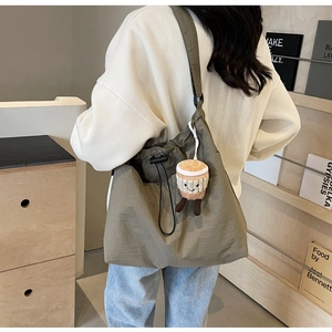 Détail du sac cabas en nylon vert olive avec fermeture à cordon et breloque peluche café