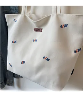 Detailed close-up of large canvas tote bag with QZBG embroidery and leather logo tag