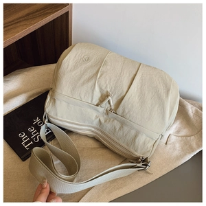 Detail of off-white nylon crossbody bag showing multiple zippers and wide strap