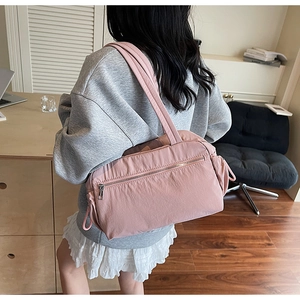 Detail of pink nylon tote bag with wide shoulder strap and functional front zipper pocket