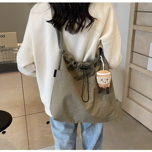 Détail du sac fourre-tout en nylon kaki avec cordon de serrage et charm peluche café