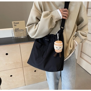 Détail du grand sac cabas en nylon noir avec bandoulière réglable et breloque en peluche