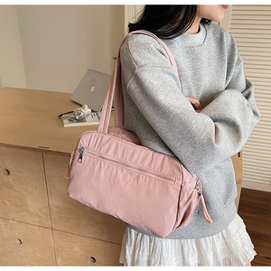 Pink nylon tote bag detail with side drawstring pocket and durable zippers shown in use