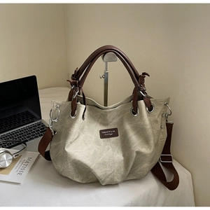 Detail of vintage canvas tote bag with brown leather handles and silver metal hardware