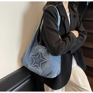 Close-up of a blue denim tote bag featuring a large 3D embossed star and Hobo style