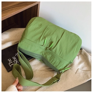 Detail of green nylon crossbody bag with functional zip pockets and woven strap