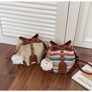 Detail of woven straw bucket bags with leather trim and plush sheep pendant decor