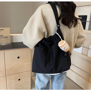 Détail du grand sac cabas noir en nylon avec poche à cordon et pendentif en peluche doux