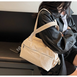 Detail of off-white pleated nylon tote bag with dual silver zipper pockets on the front