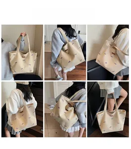 Detail view of large canvas tote bag with colorful GUNG embroidery and long shoulder straps