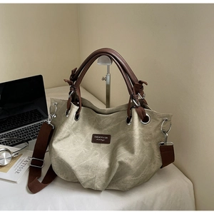 Detail of grey canvas tote bag with brown leather straps and artistic lifestyle props