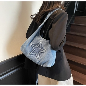 Detail of blue denim tote bag featuring a large embossed star and vintage washed finish