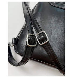 Close-up of adjustable strap with silver buckle on a black faux leather mini backpack