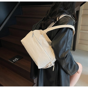 Close-up of beige canvas shoulder bag with pleated texture and metal zipper detail