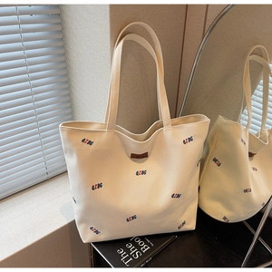 Detail view of canvas tote bag with colorful QZBG embroidery and leather brand tag