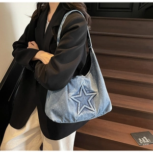 Detail of light blue denim tote bag with star embroidery worn by model on shoulder
