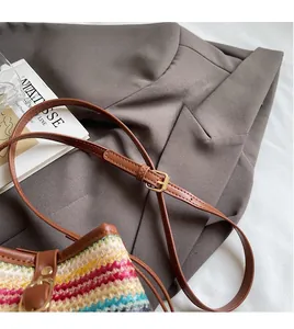 Detail of adjustable brown shoulder strap and woven texture on bohemian straw bucket bag