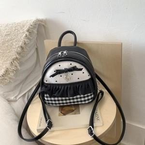 Detail of stylish backpack with heart print, black bow and metal heart pendant