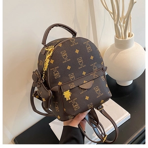 Detail of mini dark brown bear pattern backpack with golden zipper and plush charm